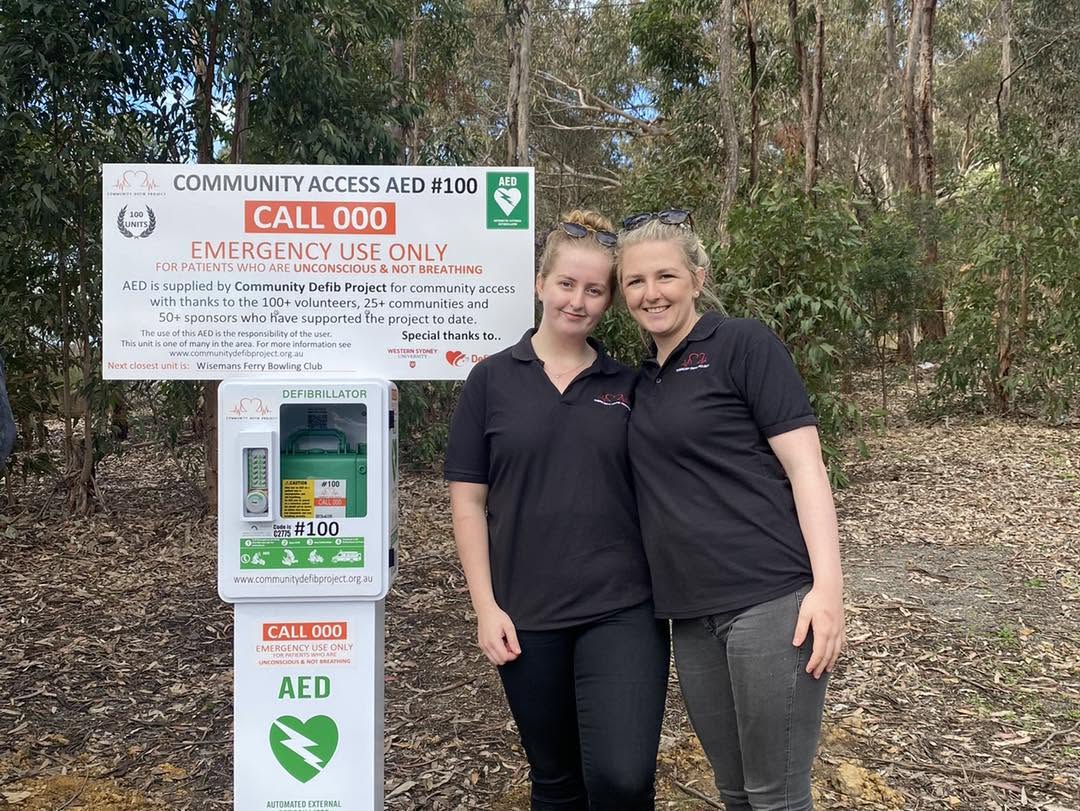 Two CDP volunteers beside community AED 100